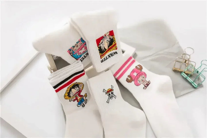 One Piece Luffy and Chopper socks, white with embroidered designs, neatly folded in a box with denim background for display.