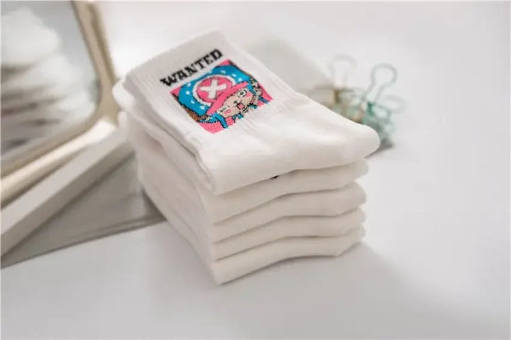 One Piece Luffy and Chopper socks, white with embroidered designs, neatly folded in a box with denim background for display.