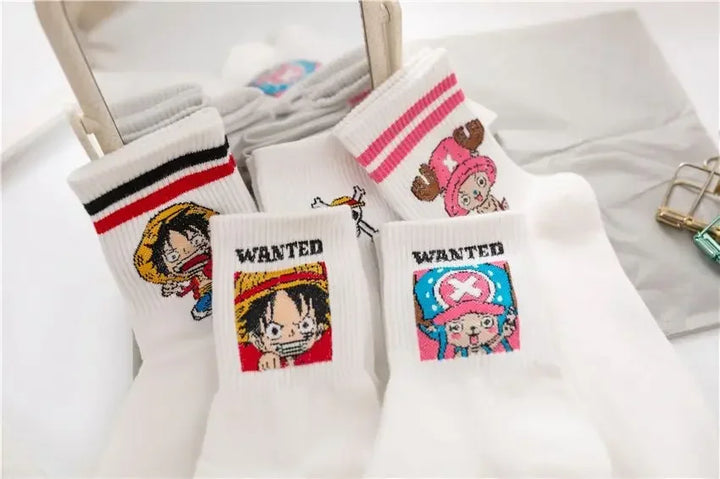 One Piece Luffy and Chopper socks, white with embroidered designs, neatly folded in a box with denim background for display.