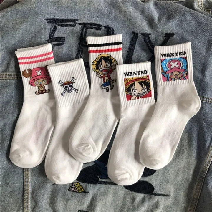 Box of folded socks with cartoon characters on each pair, placed on a denim background with embroidered designs.